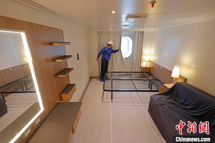 工作人員在船內(nèi)調(diào)試客房窗簾?！∫罅⑶?攝